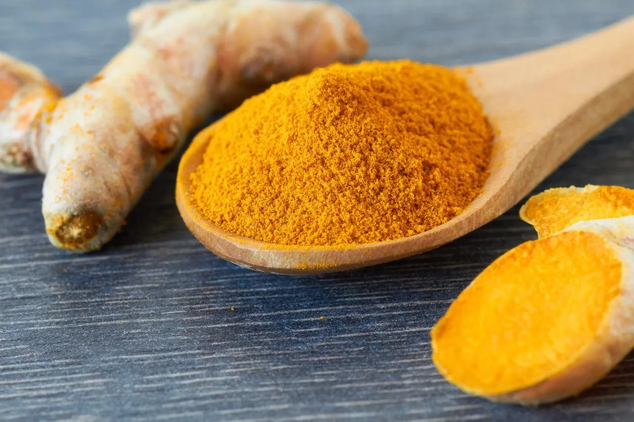 turmeric root and turmeric powder on wooden background