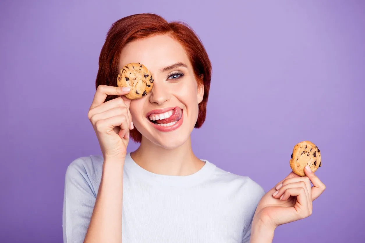 close up portrait of stylish beautiful pretty cheer cute she her girl hiding eyes behind cookies with stick out tongue loves choco very much isolated on violet background