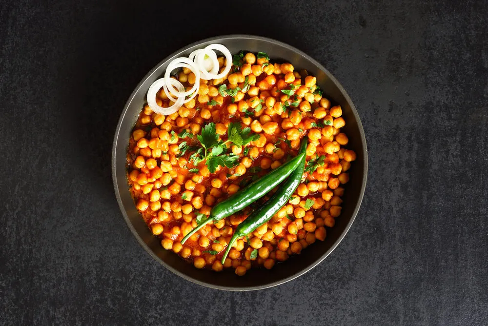 crispy roasted chickpeas in pan indian style dish over black stone background with free text space vegetarian vegan food concept top view, flat lay