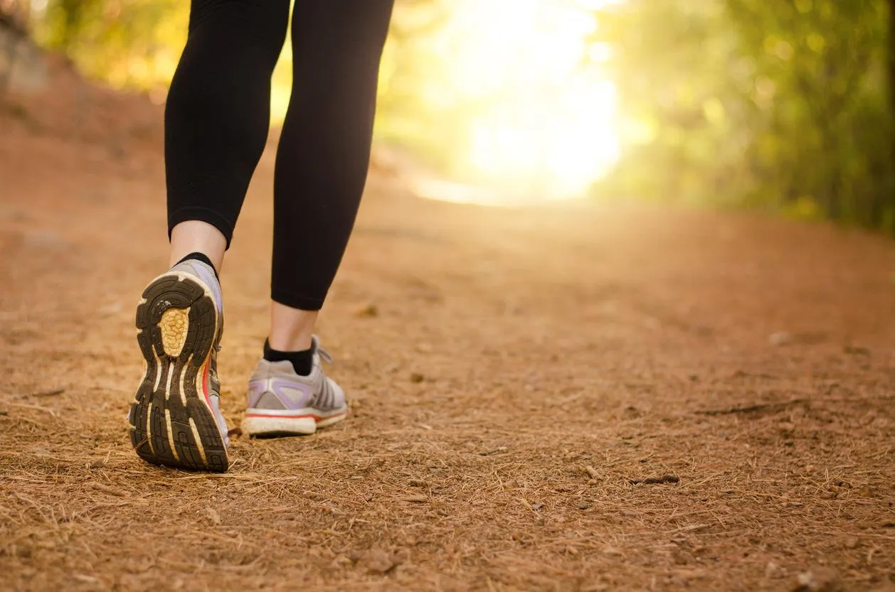 pair of legs walking on a trail in nature towards the light