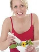 jeune femme tenant un mortier rempli de plantes et fleurs medicinales