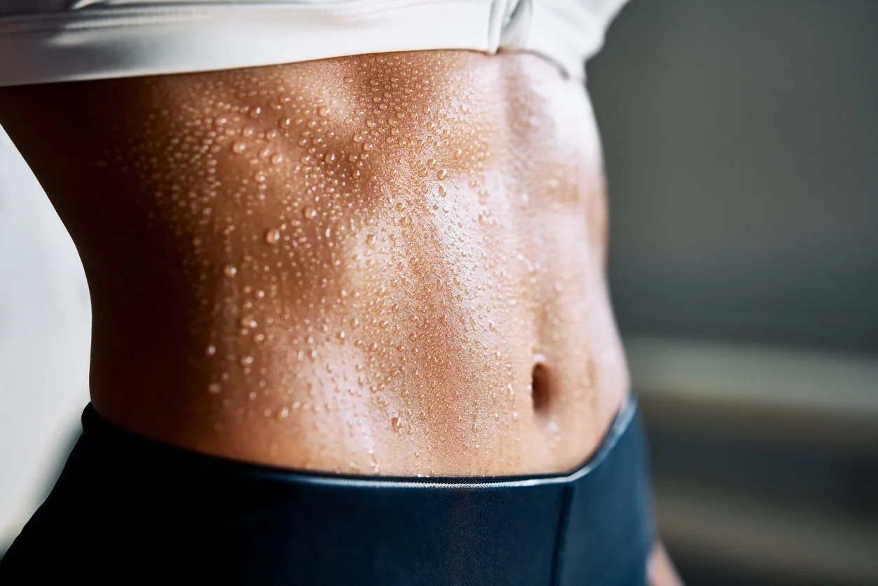 close up of fit woman torso with sweat on skin after workout female with perfect abdomen muscles