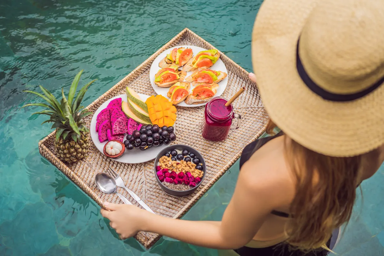 breakfast tray in swimming pool, floating breakfast in luxury hotel girl relaxing in the pool drinking smoothies and eating fruit plate, smoothie bowl by the hotel pool exotic summer diet tropical beach lifestyle bali trend