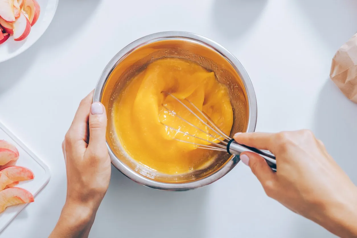 close-up female hands whisk eggs for apple pie, view from above flat lay arrangement woman cooking fruit cake
