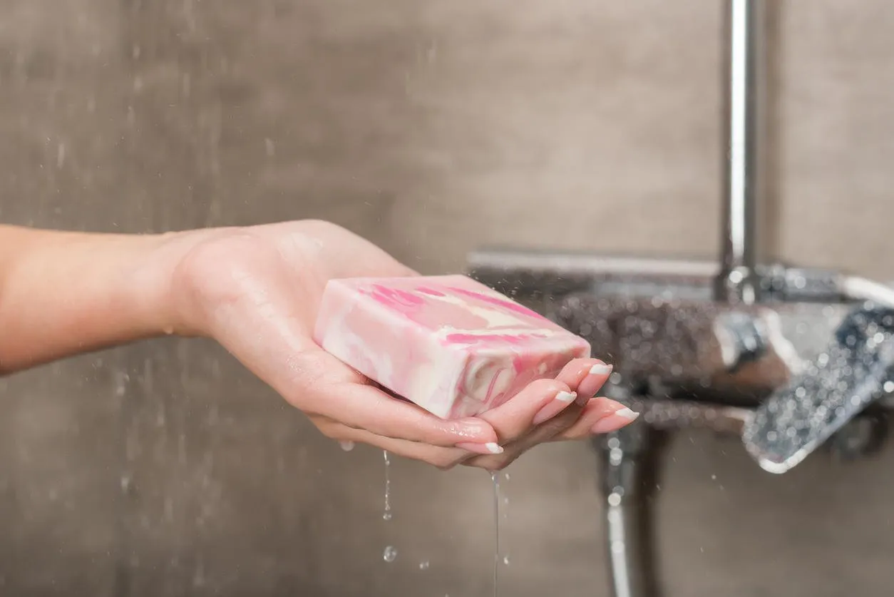 cropped image of girl holding soap in hand in a shower