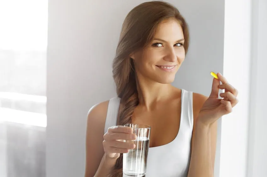 régime alimentaire vitamines saine alimentation, mode de vie gros plan d'heureuse femme souriante prenant la pilule avec de l'huile de foie de morue oméga-3 et tenant un verre d'eau fraîche dans la vitamine d matin, e, une capsules d'huile de poisson