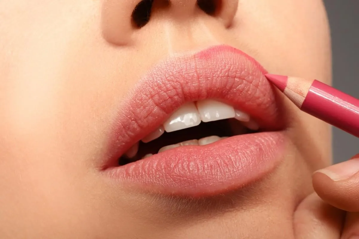 lips of beautiful young woman applying makeup, closeup