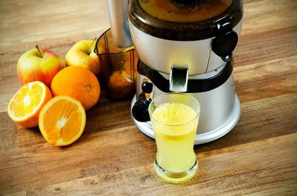 presse-agrumes et jus d'orange sur fond en bois