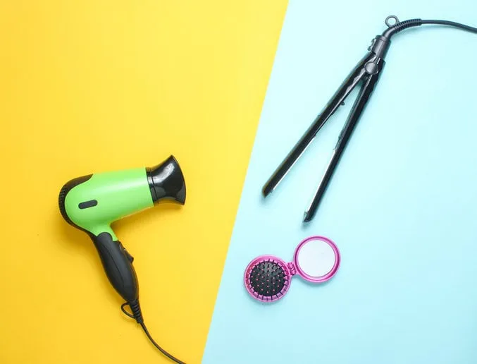 hairdryer, curling iron, hairbrush mirror on a pastel colored background beauty and fashion objects for hair care top view