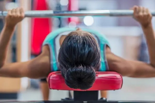 séance d'entraînement de la jeune femme avec haltères sur le banc dans la salle de fitness