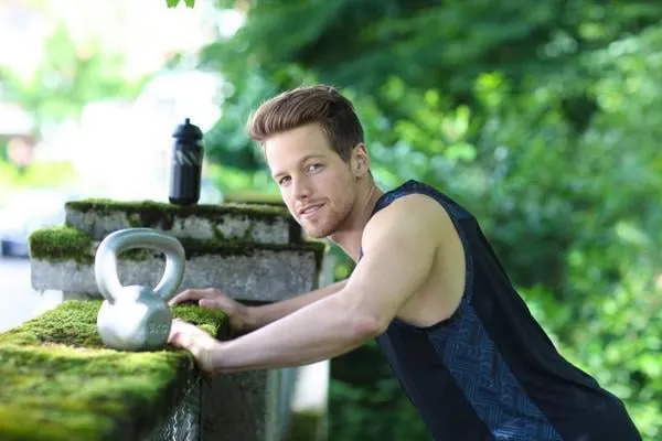 homme à l'entraînement en plein air avec le kettlebell dans le parc