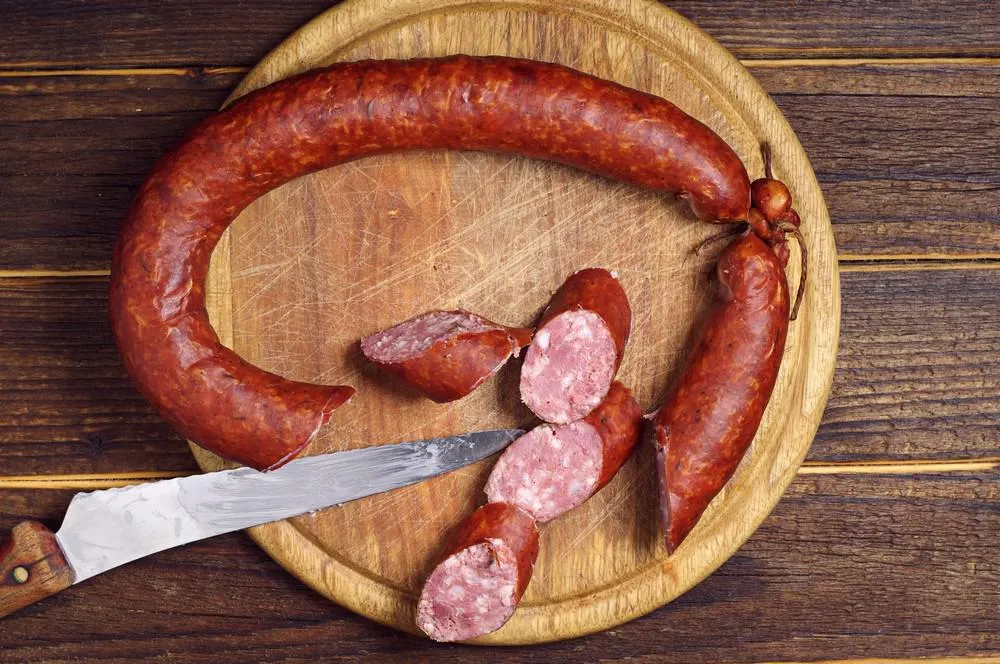 saucisse fumée grasse sur une planche de cuisine, vue de dessus