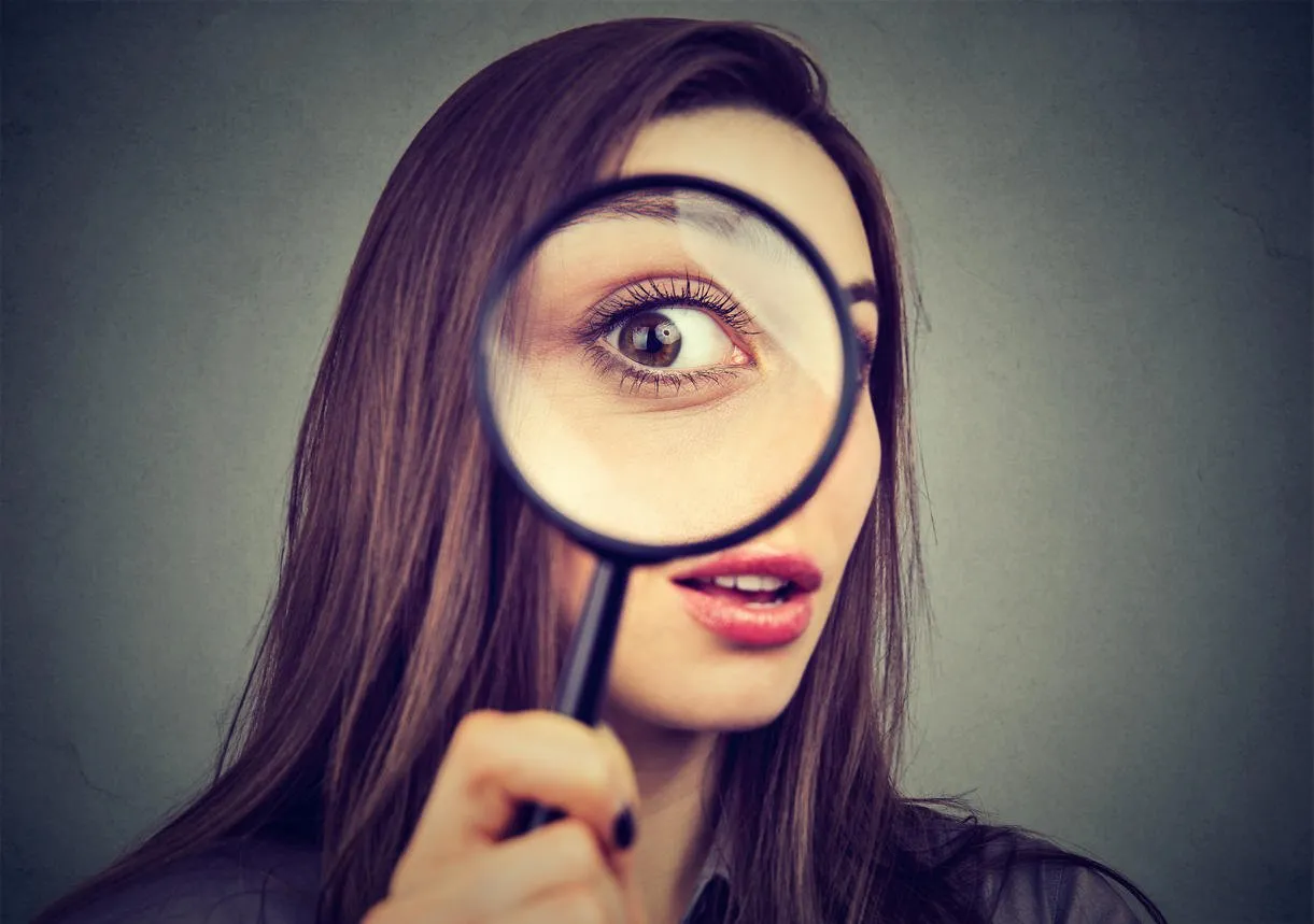 curious woman looking through a magnifying glass