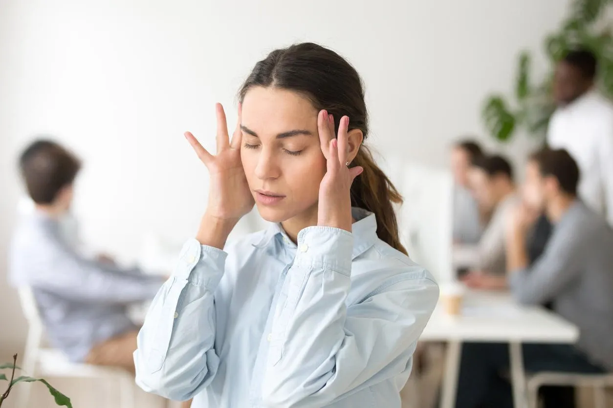 stressed frustrated young woman employee feeling pain unwell dizzy, tired of difficult office job, suffering from panic attack, hormone imbalance or having headache migraine massaging temples at work