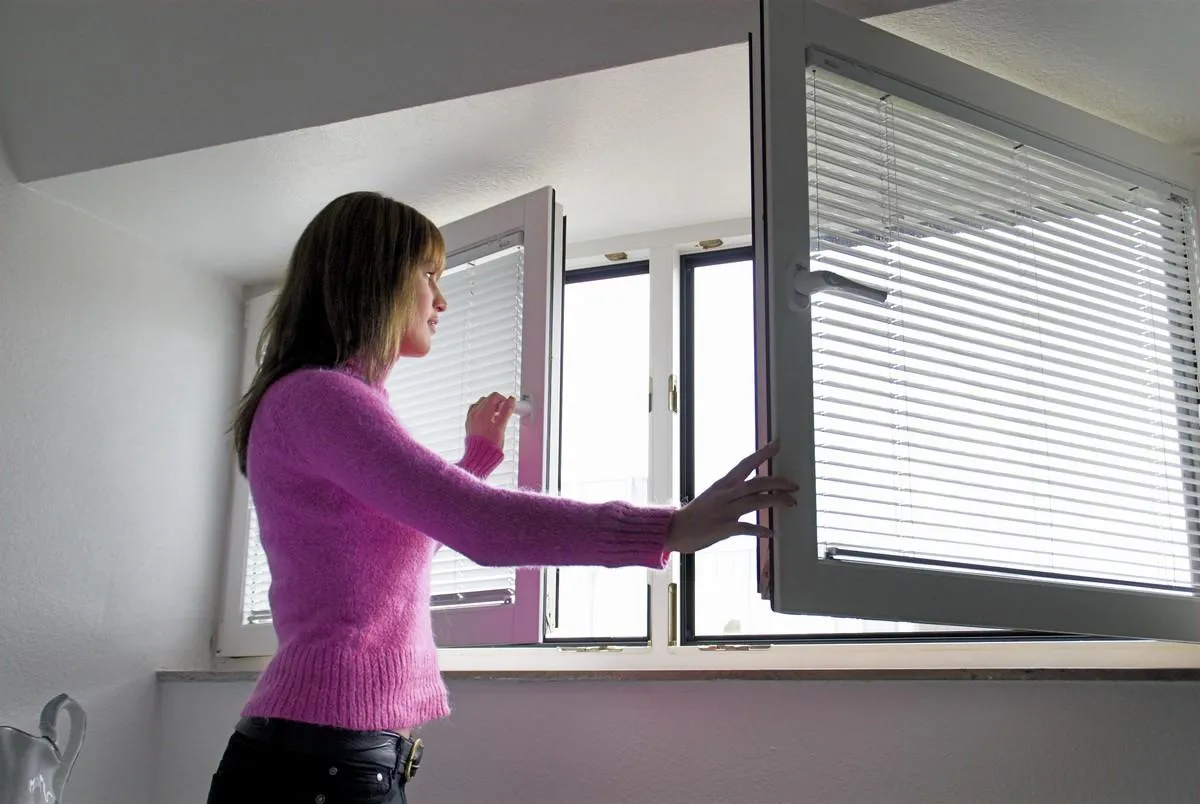 frau lüftet ein zimmer