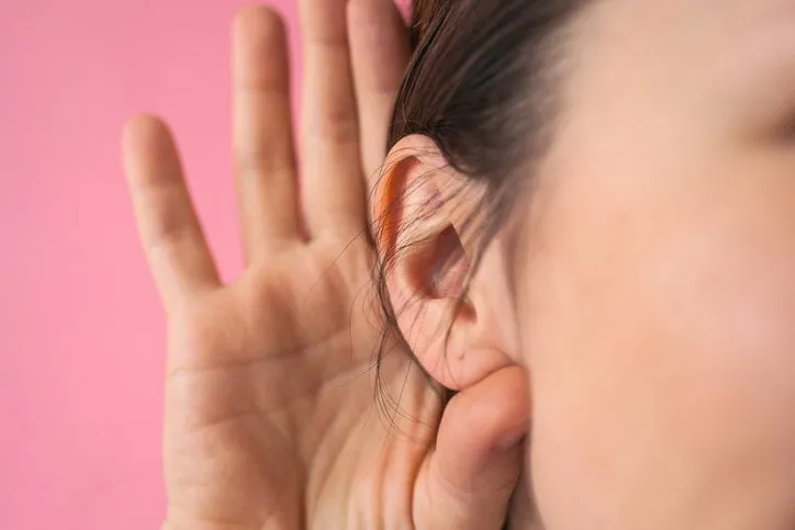 close-up of a girl holding her hand next to her ear the concept of chatter, gossip, news or secrets