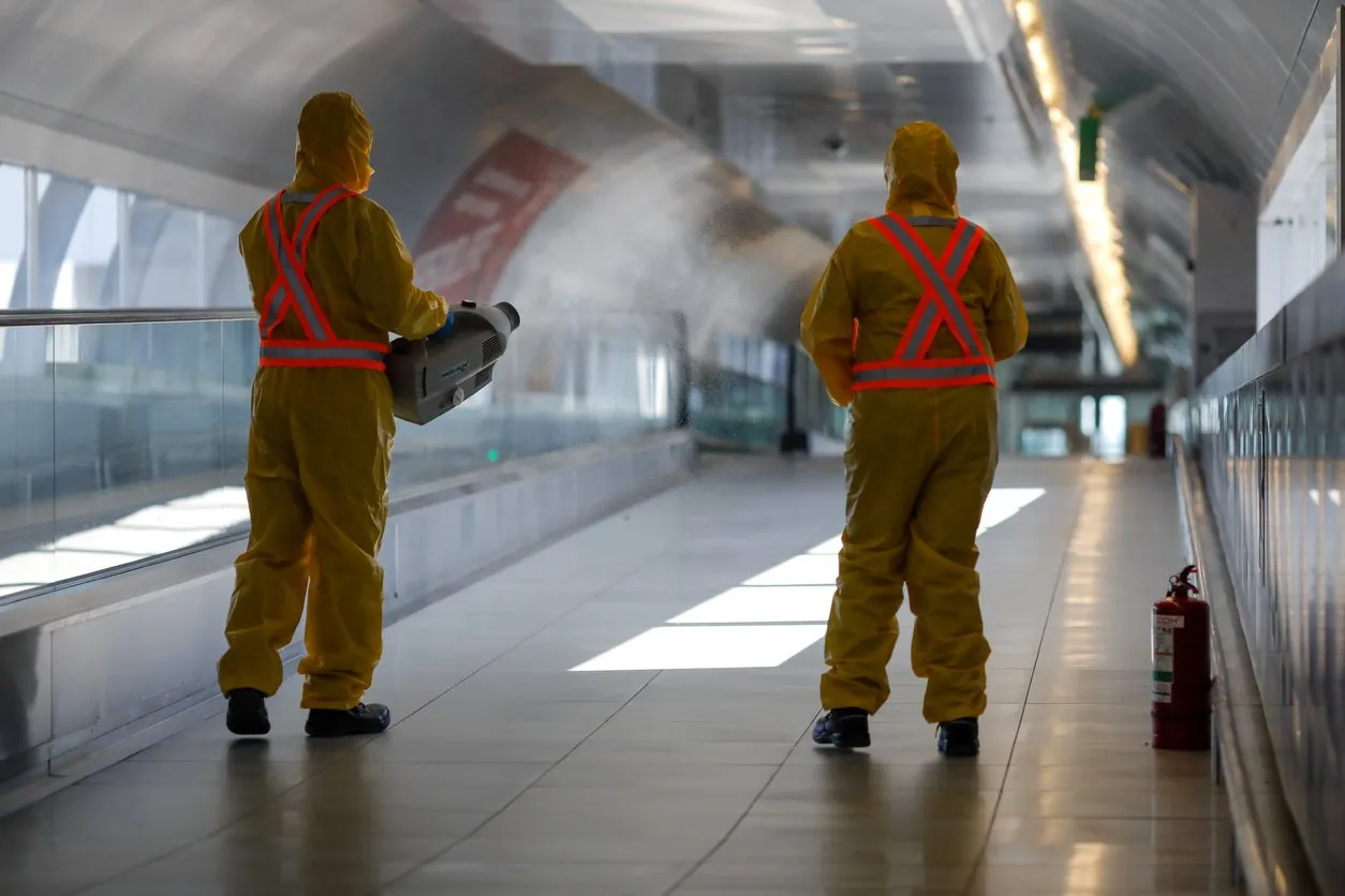 otopeni, romania - february 25, 2020  people wearing protective suits spray disinfectant chemicals on the henri coanda international airport to prevent the spreading of the coronavirus