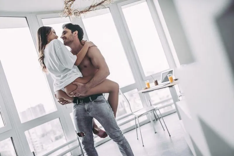 good morning young romantic couple on light modern kitchen with panoramic windows sexy young woman in underwear and shirtless handsome man are spending time together passionate lovers having sex on kitchen