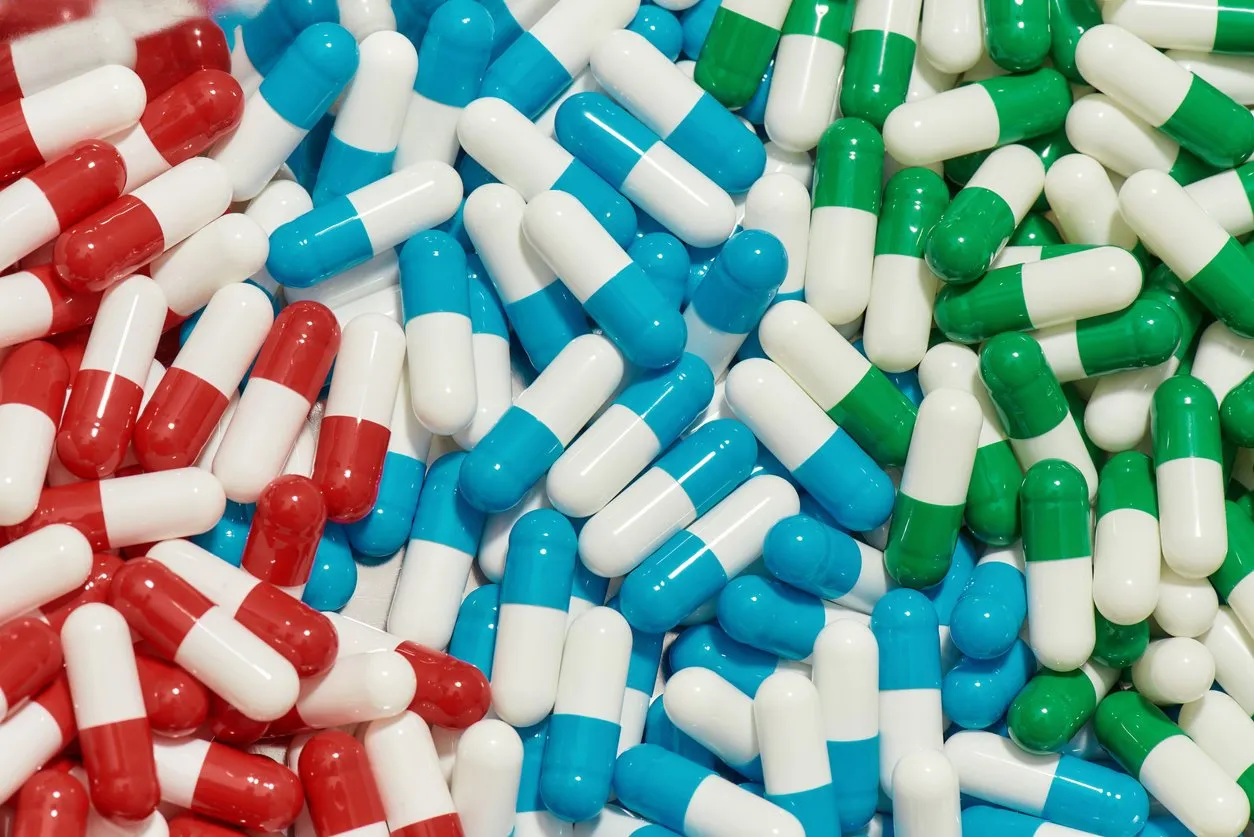 close up of different pills, capsules lying randomly health care, vitamins and treatment concept main focus on red capsules horizontal shot