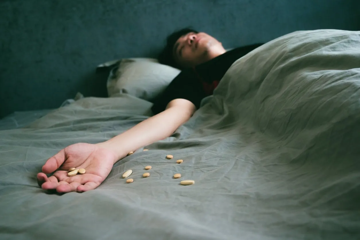 teenager asian man pouring many pills into his hand and sleeping on the bed sick asian man shocked and unconsciousness from drug overdose