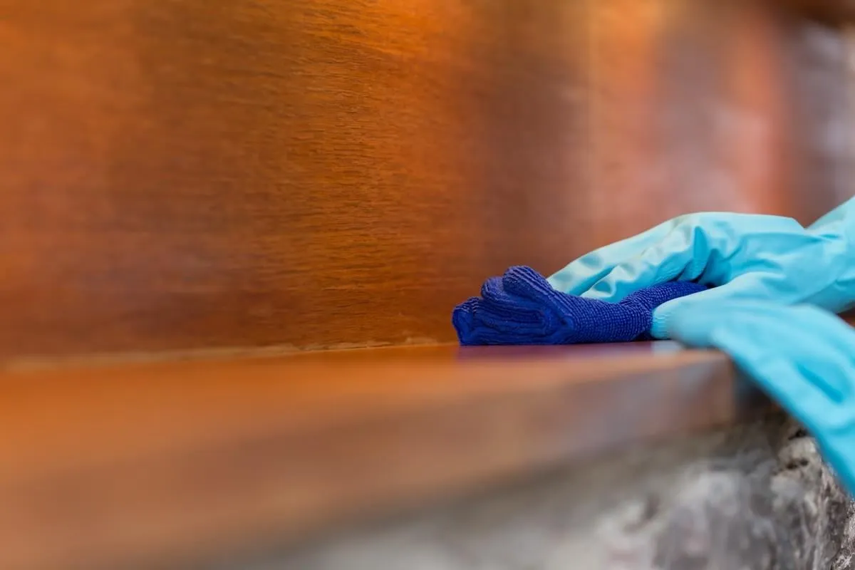 maid cleaning table with blue glove and microfiber in living room,cleaning service concept