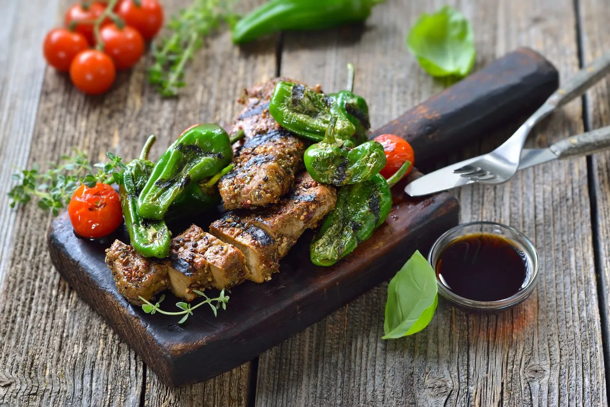 grilled vegan seitan steaks with pimientos de padron and served with a herb soy sauce on a rustic wooden background