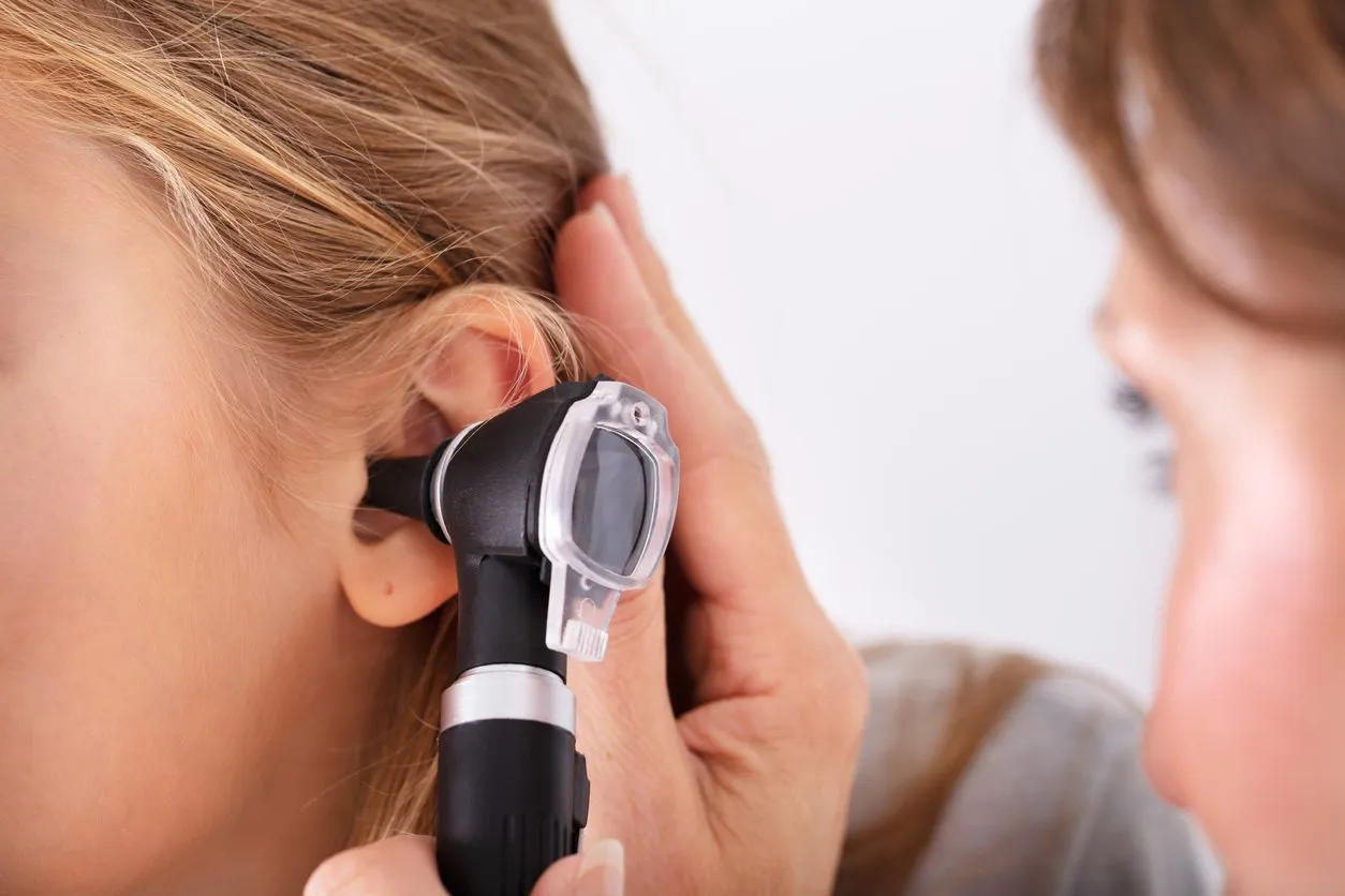 close-up of doctor checking happy girl's ear with otoscope