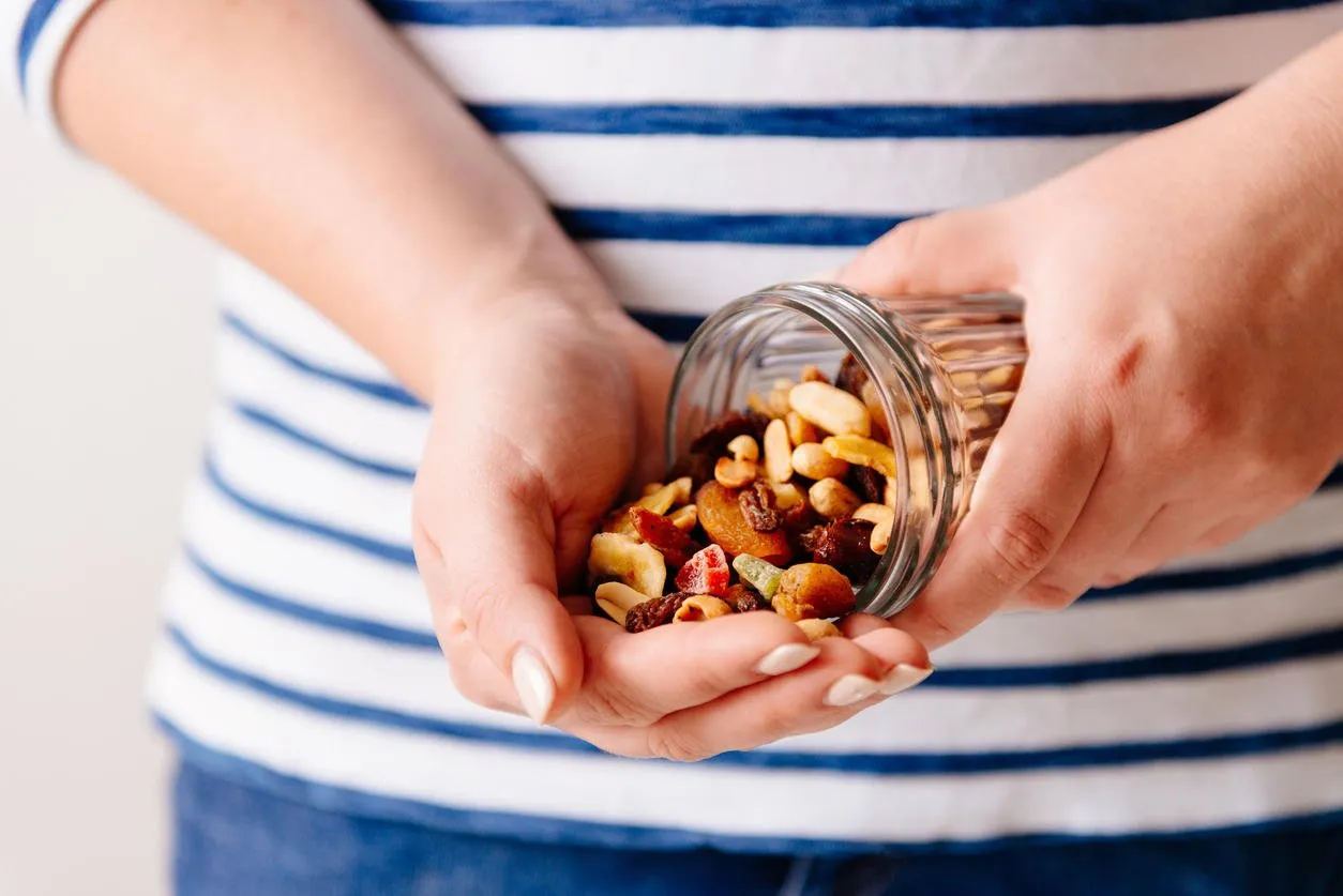 hands holding a jar of nuts and dried fruits healthy breakfast sweet and healthy food, snack