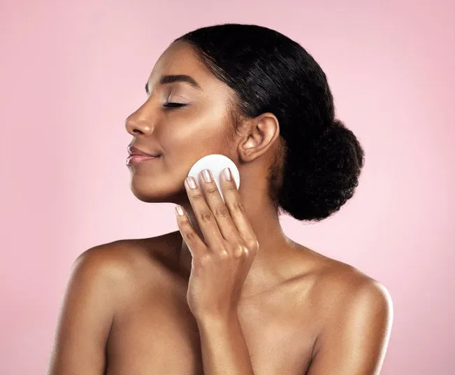studio shot of a beautiful young woman cleaning her face with cotton wool