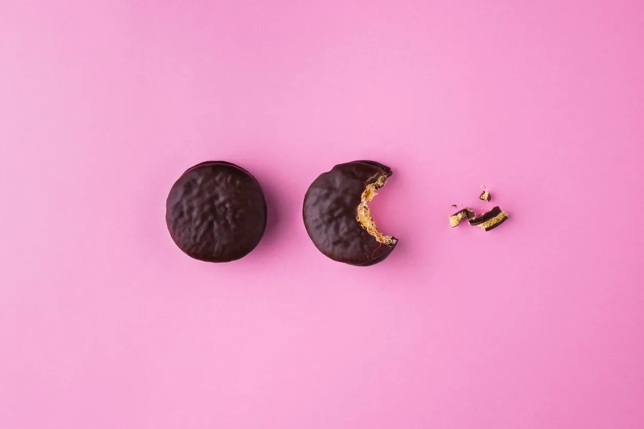 creative concept of chocolate sandwich cookies or macaroons bite on pastel pink color background food inspiration idea top view,flat lay horizontal orientation