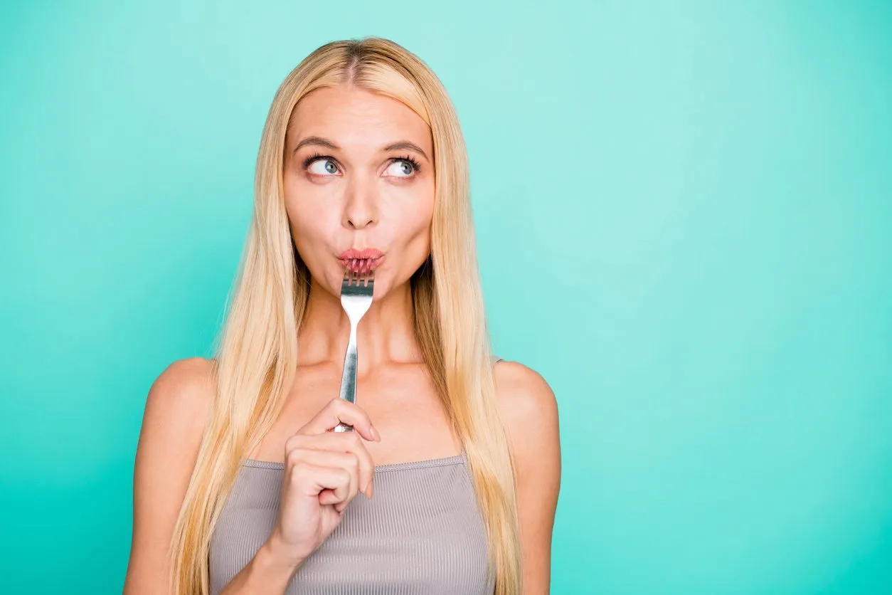 close-up portrait of her she nice attractive lovely sweet feminine girlish, straight-haired girl holding in hand kitchen ware licking fork isolated on bright vivid shine green blue turquoise background