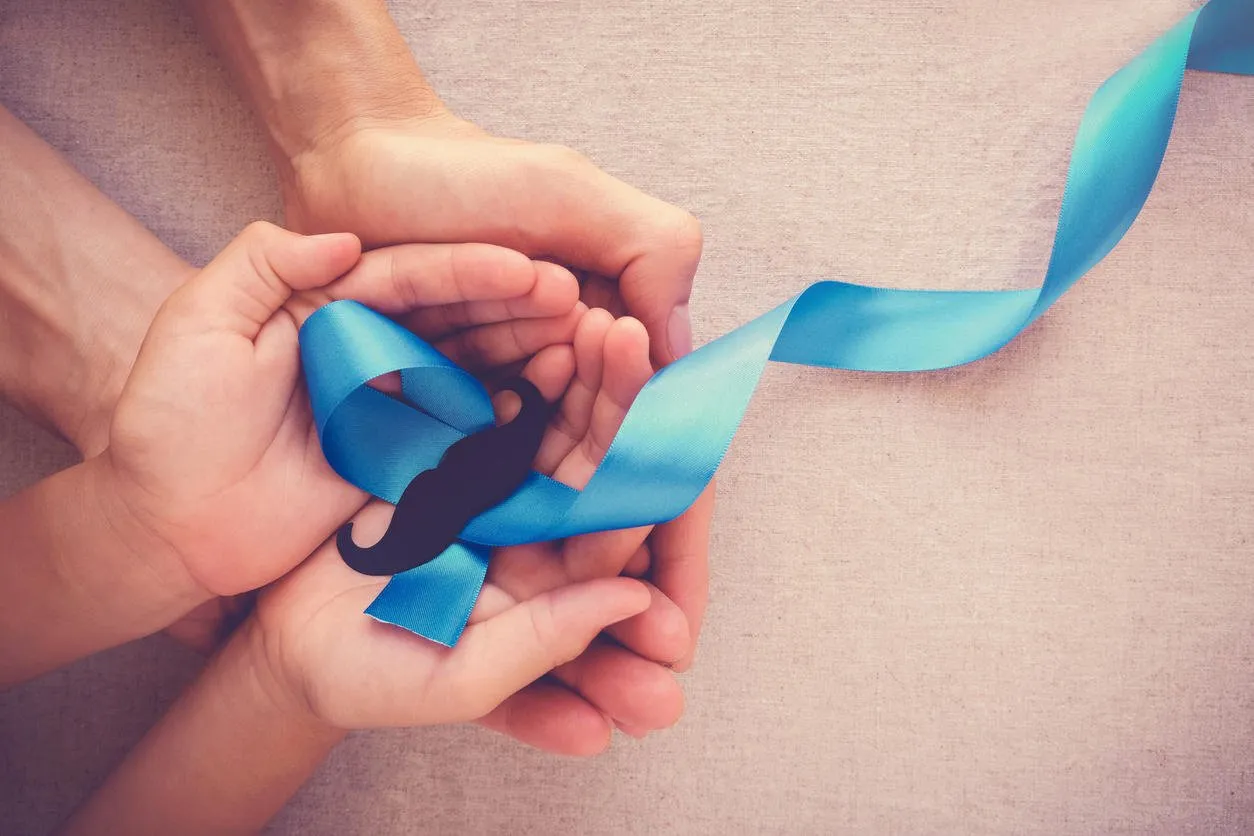 adult and child hands holding light blue ribbons with mustache , prostate cancer awareness, men health awareness, movember month
