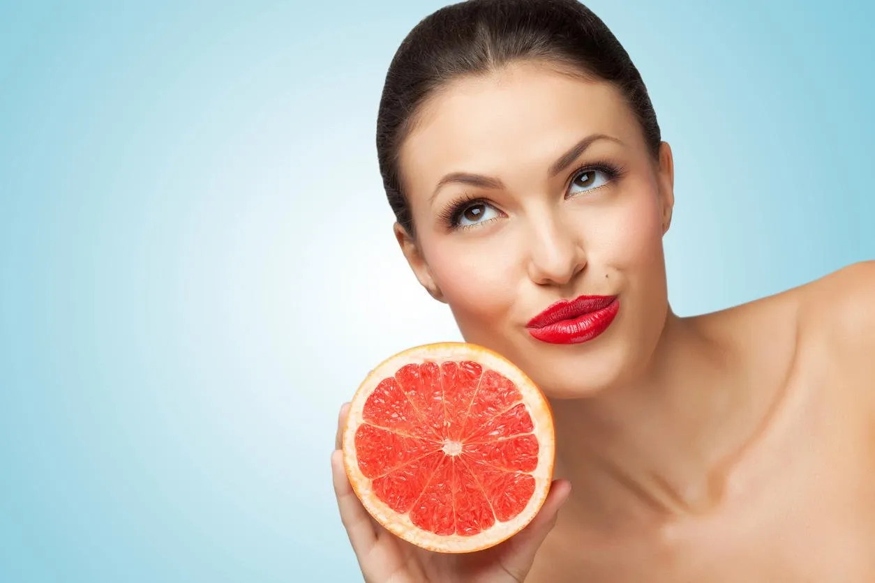 un portrait créatif d'une belle fille tenant un pamplemousse mûr