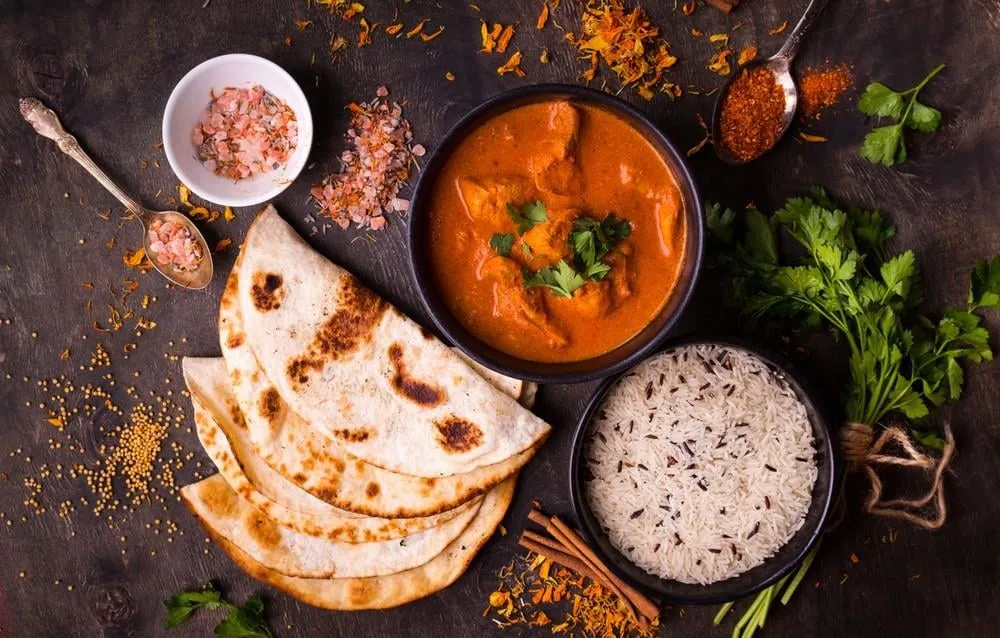 hot spicy chicken tikka masala in bowl chicken curry with rice, indian naan butter bread, spices, herbs traditional indian british dish, popular indian curry in uk top view indian food close-up