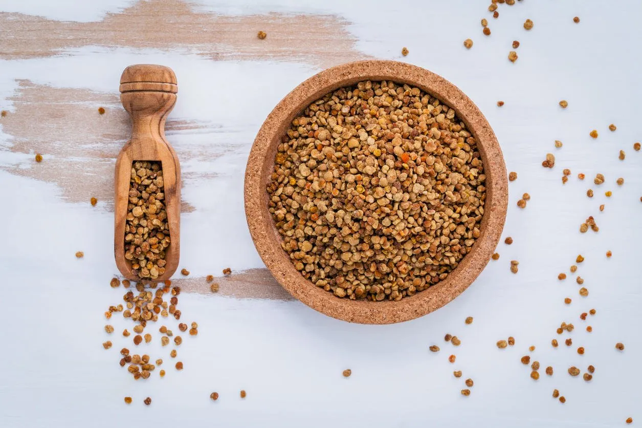 pollen d'abeille organique cru sur les granules de pollen d'abeille de planche de bois minable et propolis dans le concept d'alimentation homéopathique de pelle en bois avec pollen d'abeille plat poser sur le fond en bois