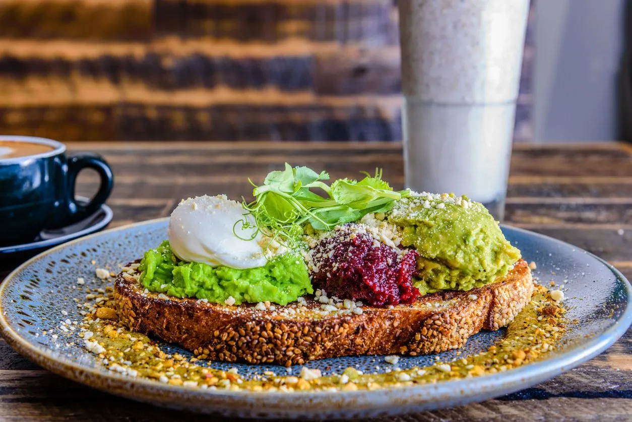a plate of smashed avocado on toast with a poached egg on top