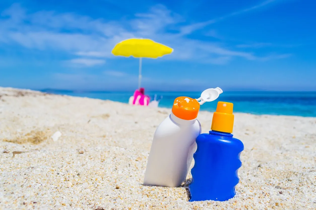 detail of suntan lotion bottles on the sand