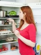 femme rousse à la recherche de quelque chose dans le réfrigérateur à la maison