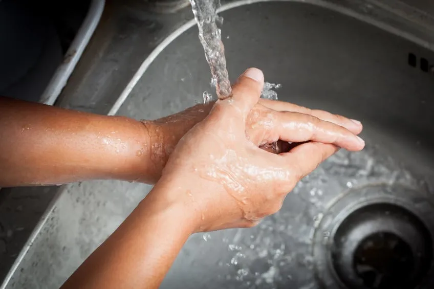 femme se laver les mains sous l'eau courante dans la cuisine