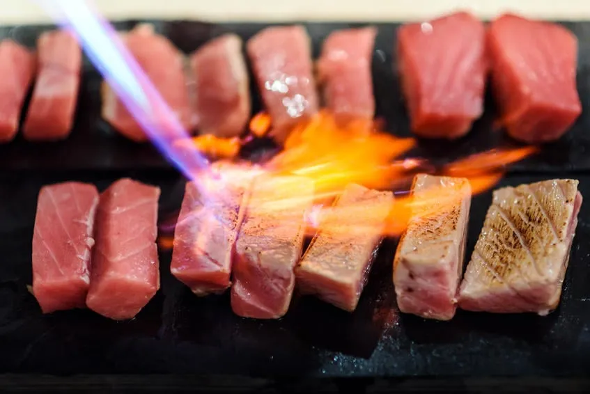 chef à l'aide d'une torche brûler sur le thon sashimi