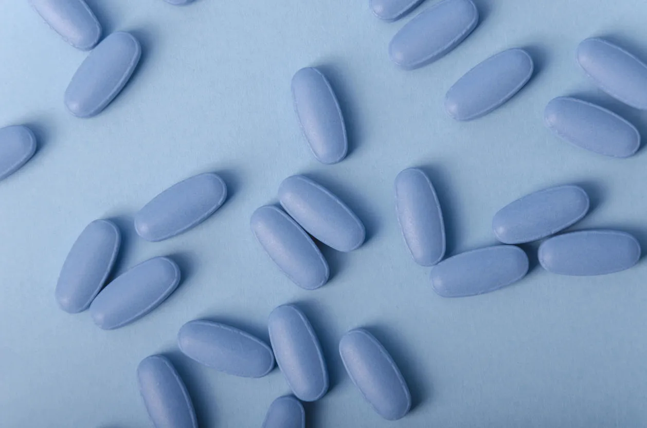 random composition of blue tablets over a light blue background for medical uses
