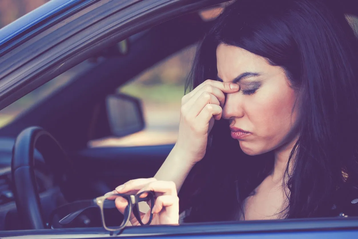 business woman having headache taking off her glasses has to make a stop after driving car on rush hour exhausted driver concept