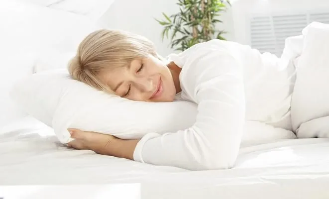 belle femme allongée dans un lit blanc