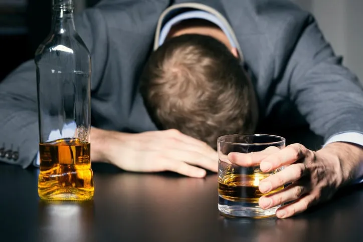 dépendance à l'alcool - homme d'affaires ivre tenant un verre de whisky sur la table