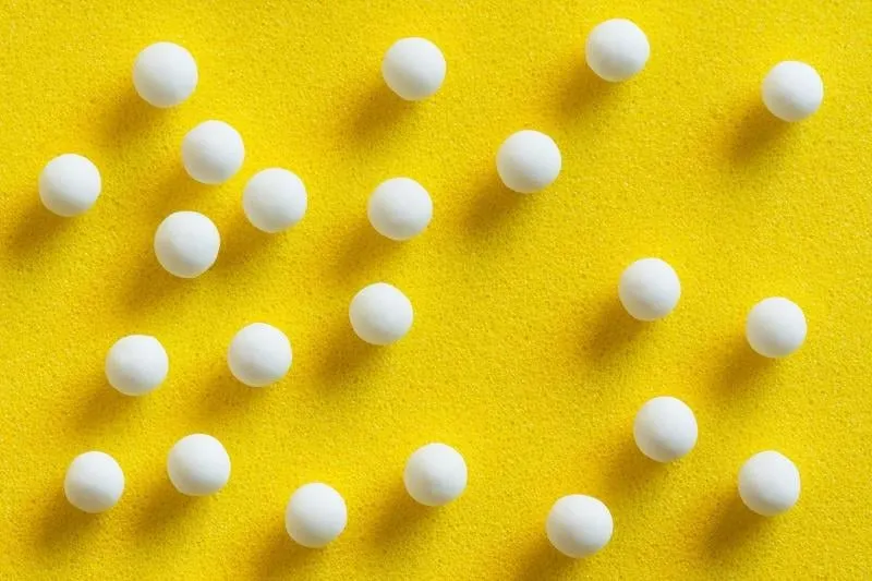 overhead view of homeopathic pills (made from inert substance - sugar lactose) scattered on a yellow surface natural light used