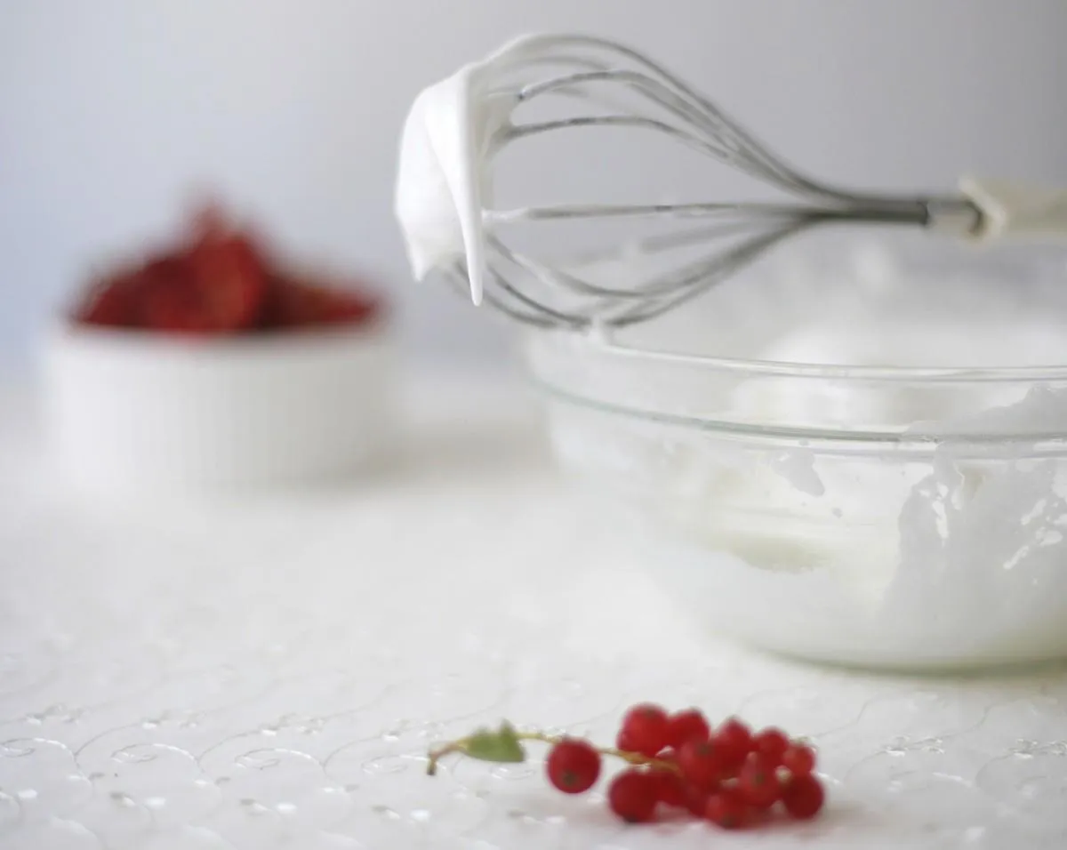 baiser auf einem schneebesen mit roten johannisbeeren