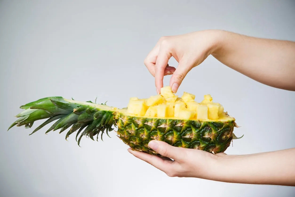 pineapple in female hands on gray background weight loss, diet