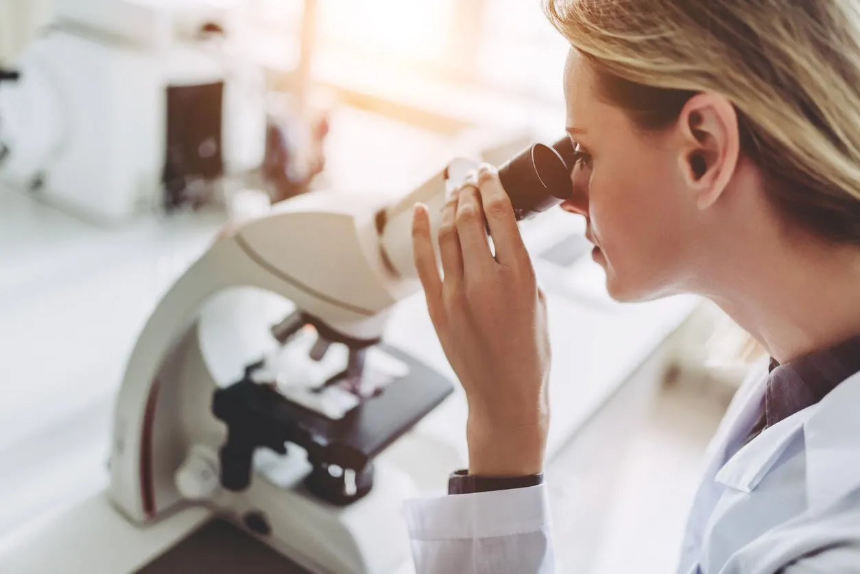 experienced female scientist is working in laboratory doing investigations with microscope