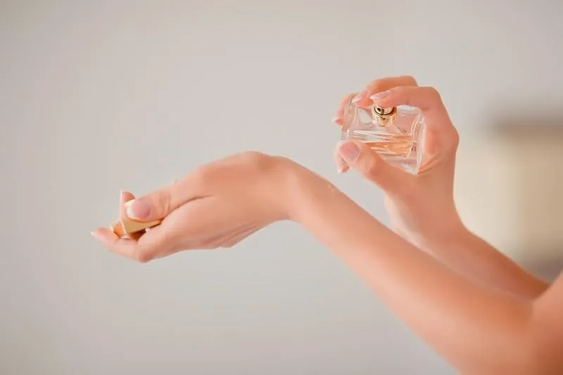 woman applying perfume on her hand, close-up