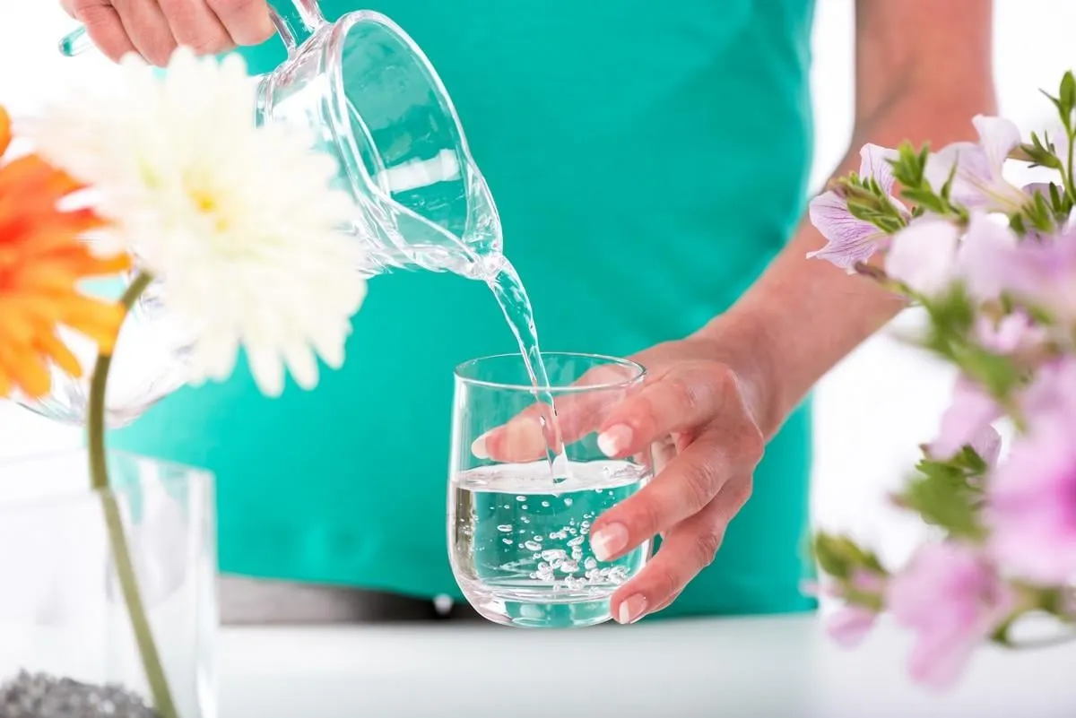 woman pouring water from a pitcher into a glass